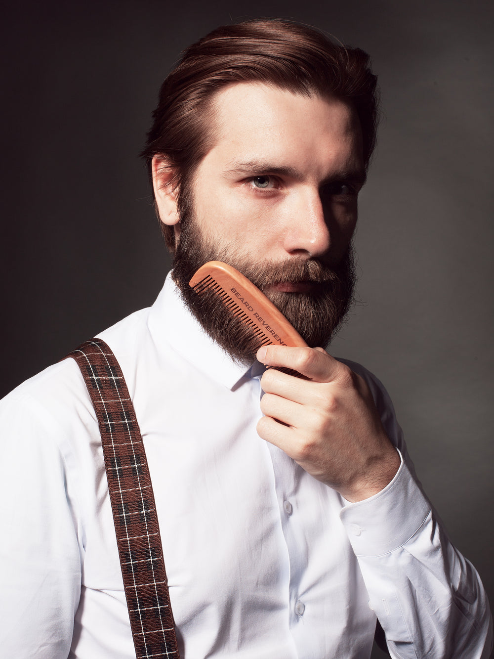 Beard Reverence beard comb being used by a well-dressed bearded man to comb his beard. 