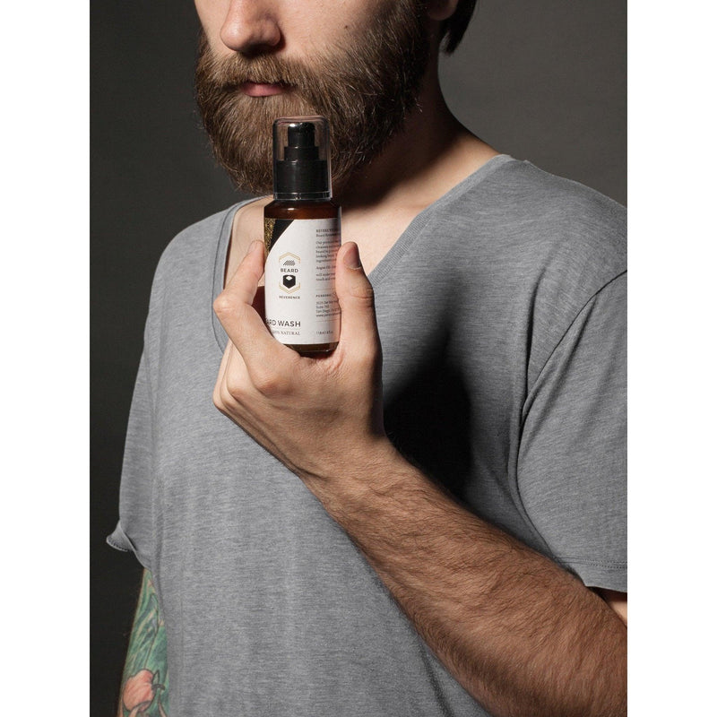 Bearded man presenting a bottle of Beard Reverence Beard Wash. 